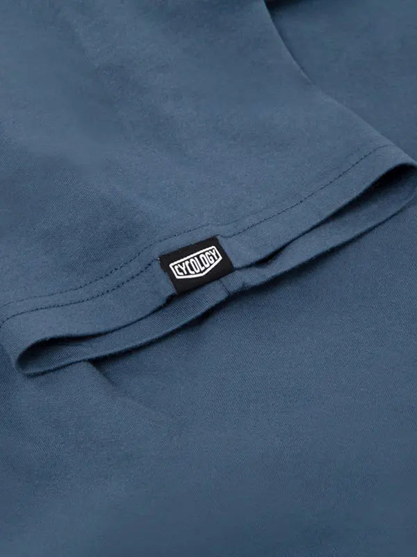 Close-up of a blue t-shirt with a brand label on the sleeve