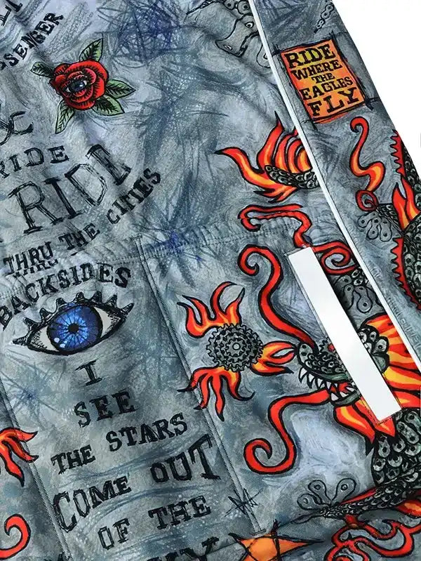Men's cycling jersey with bold tattoo-style graphics, fiery dragons, roses, and motivational phrases on gray fabric.
