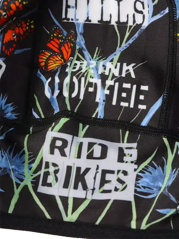 Cycling jersey with 'Drink Coffee Ride Bikes' text, butterfly and plant print on black fabric