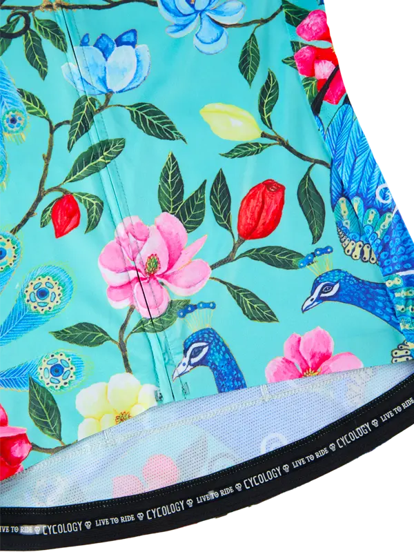 Close-up of a colorful floral and peacock pattern cycling jersey  on a teal background with 'Cycology' branding.