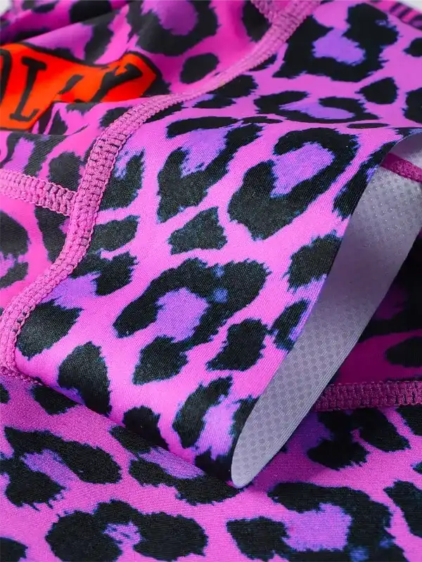 Vibrant pink leopard print cycling shorts with padded chamois and orange logo detail