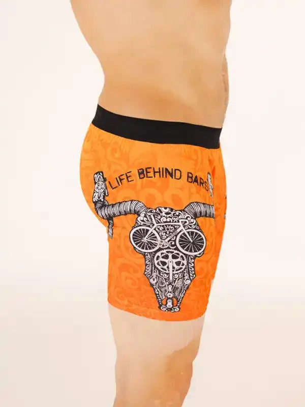Men's orange cycling shorts with skull and bike graphic, 'Life Behind Bars' text, black waistband