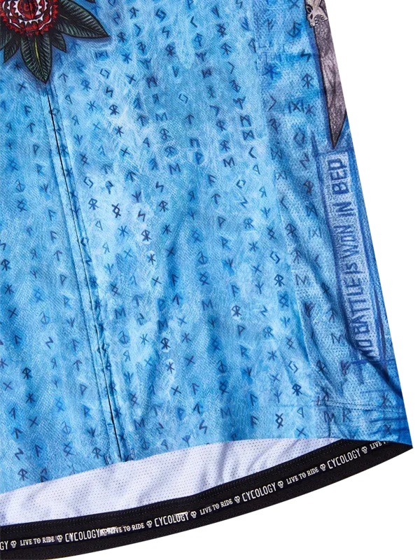 Blue cycling jersey with rune pattern, floral design, and 'The Battle Is Won In Bed' text detail