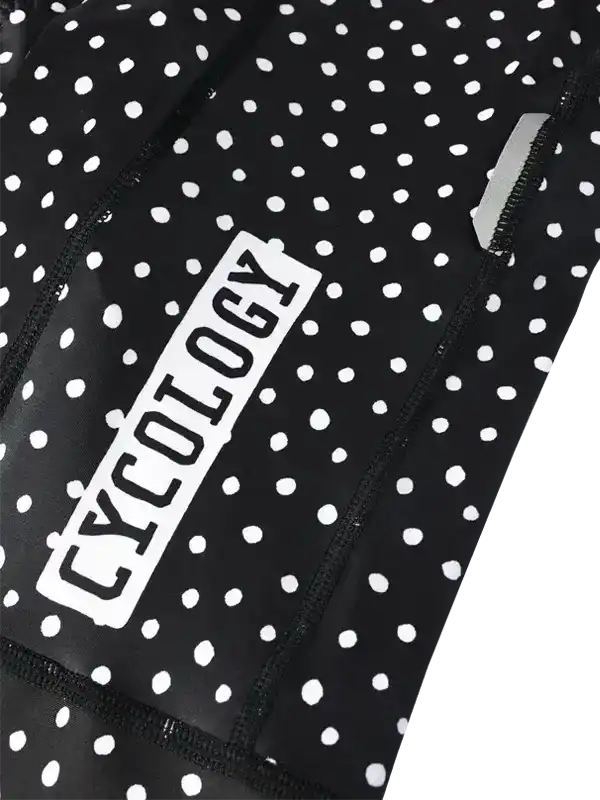 Black and white polka dot cycling jersey with 'CYCOLOGY' logo, featuring zipper pocket and performance fabric.