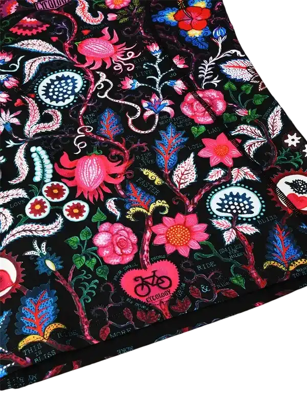 Vibrant floral cycling apparel with bold pink, blue, and red patterns on black fabric, featuring bike motifs and ride-themed text.