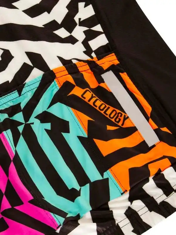 Vibrant geometric cycling shorts with bold black, orange, teal, and pink patterns, featuring reflective strip and 'CYCOLOGY' branding.