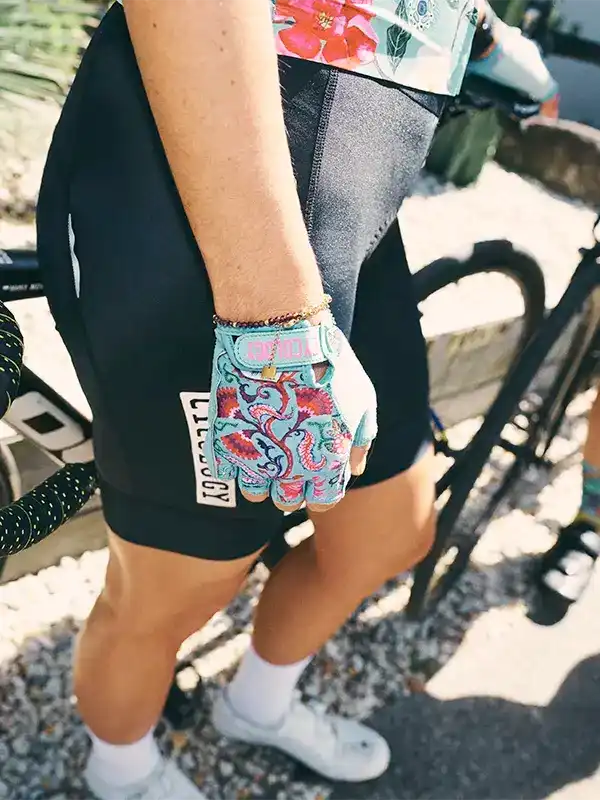 Women's cycling shorts with floral gloves, standing by bike outdoors