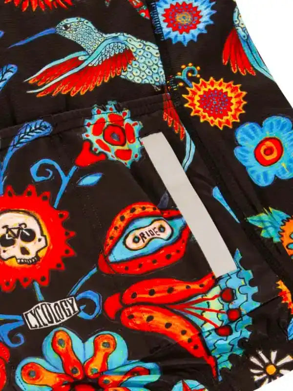 Vibrant cycling shorts with hummingbird, skull, and floral print on black fabric, featuring reflective strip.