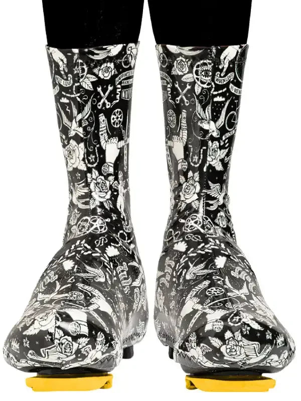 Black and white patterned cycling shoe covers with floral and bike motifs, worn over cleats