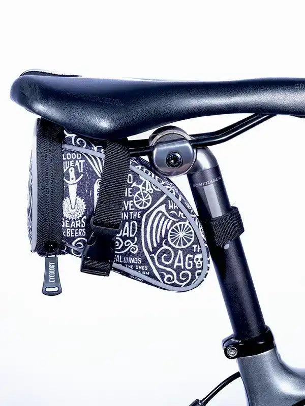 Black cycling saddle bag with white graphic print, attached to bike seat post, ideal for road rides