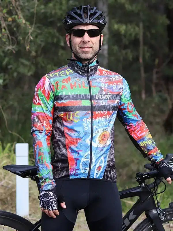 Man wearing colorful graphic cycling jersey and black helmet, standing with road bike outdoors