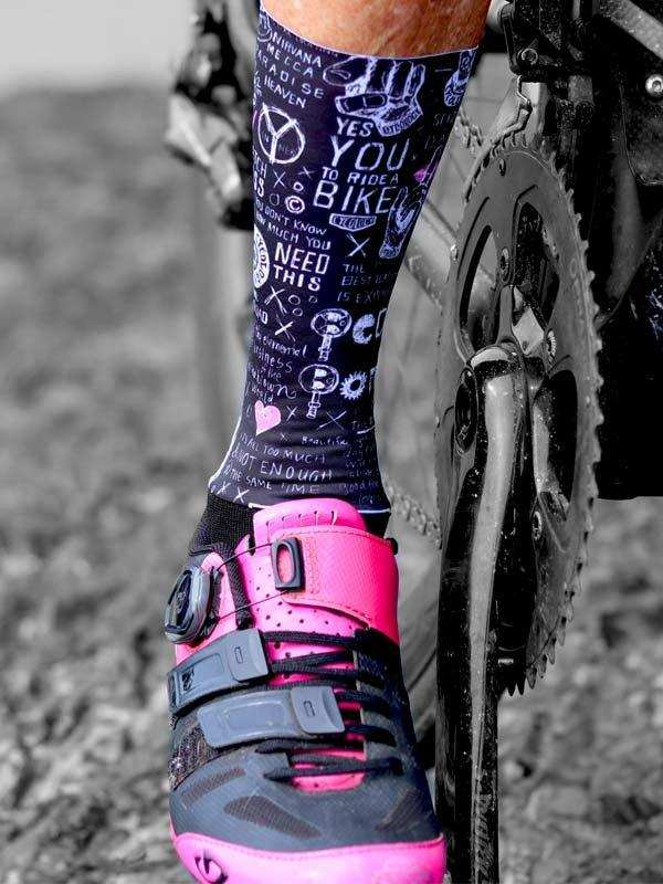 Cycling socks with bike-themed graphics paired with pink cycling shoes on a bike pedal