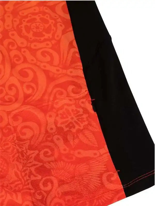 Vibrant orange cycling jersey with intricate chain and swirl pattern, black side panel, red stitching detail