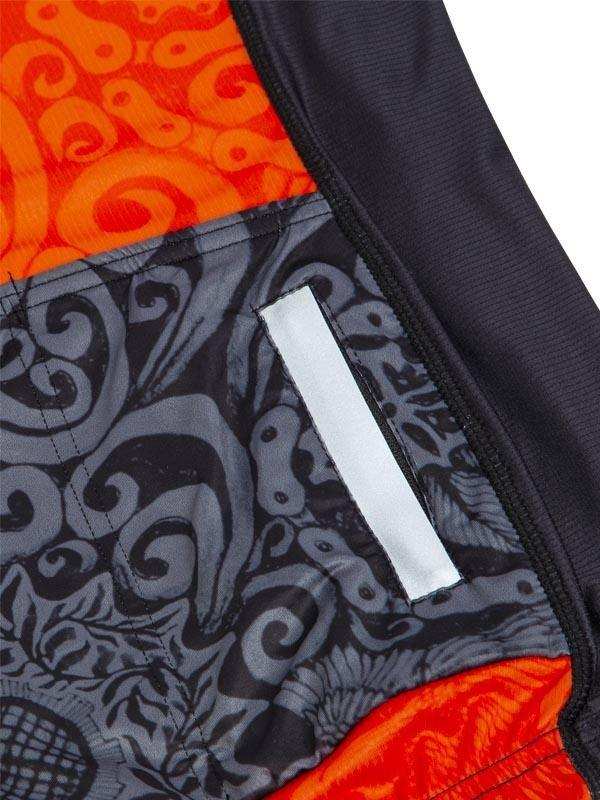 Men's cycling shorts with bold orange and gray Maori-inspired pattern and reflective strip
