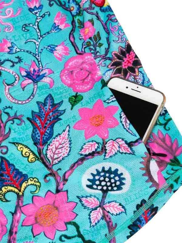 Vibrant floral cycling jersey pocket holding smartphone, featuring pink and blue botanical print on teal fabric.