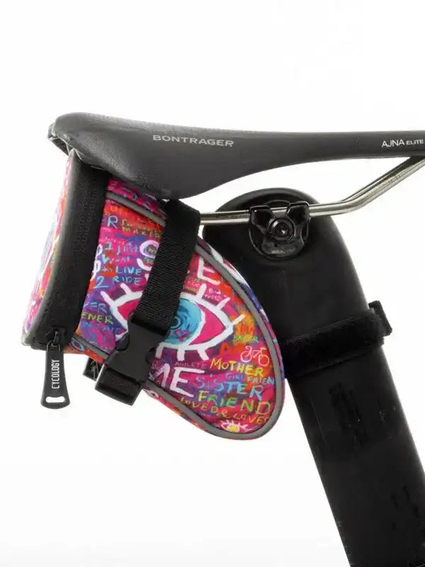 Colorful cycling saddle bag with graffiti art, attached to Bontrager bike seat for road or mountain biking storage.