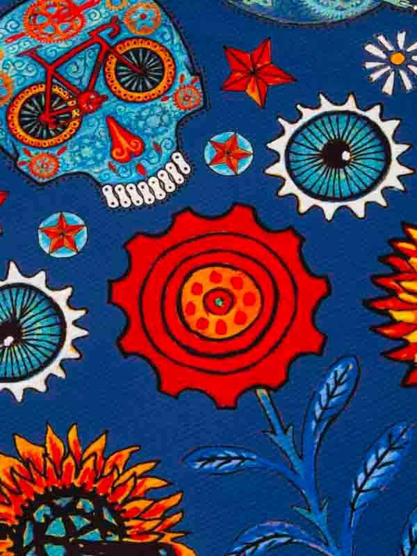 Vibrant cycling gear fabric with sugar skull, gears, and sunflowers on blue background
