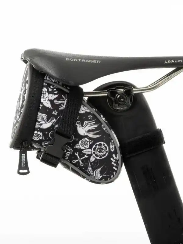 Black and white patterned cycling saddle bag with bird and gear designs, attached to Bontrager seat