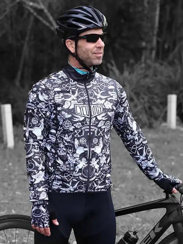 Man in black and white patterned cycling jersey with helmet, standing beside road bike outdoors