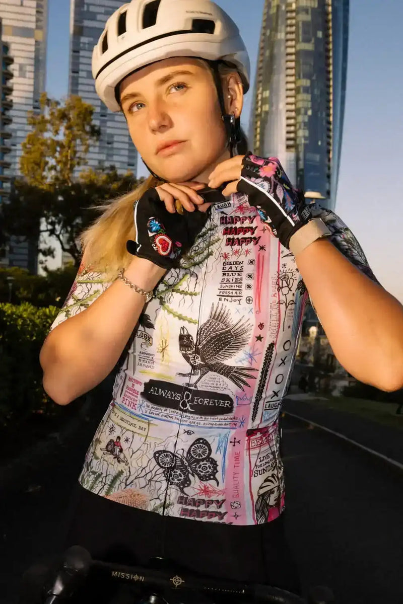 Woman in colorful graphic cycling jersey and helmet, urban city backdrop, ready to ride.