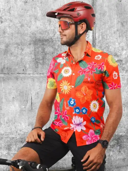 Man wearing vibrant floral cycling jersey and red helmet, ready for a ride