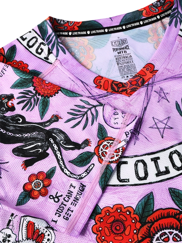Close-up of a purple cycling jersey with colorful designs and brand logos.