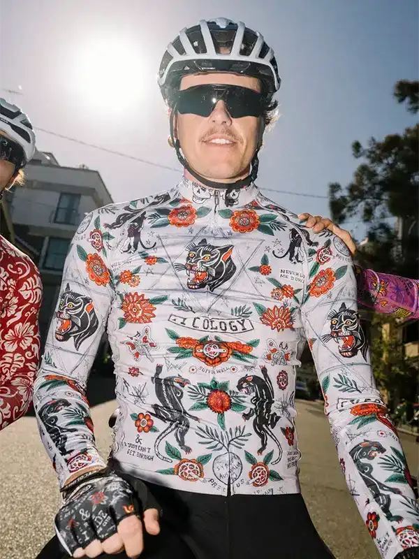 Man wearing vibrant floral and panther print cycling jersey with helmet and sunglasses outdoors