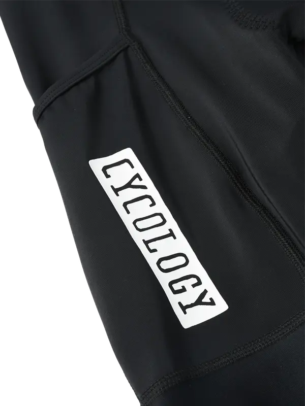 Close-up of a black garment featuring a white rectangular  branding on the side cargo pocket with the word 'CYCOLOGY' printed in black.