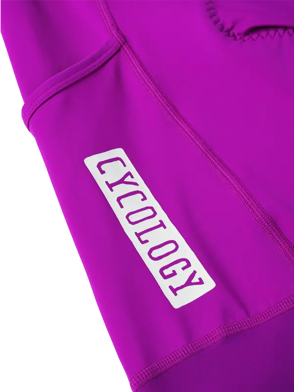 Close-up of magenta cycling bib leg side with a white rectangular patch containing the brand word 'CYCOLOGY' in matching magenta.