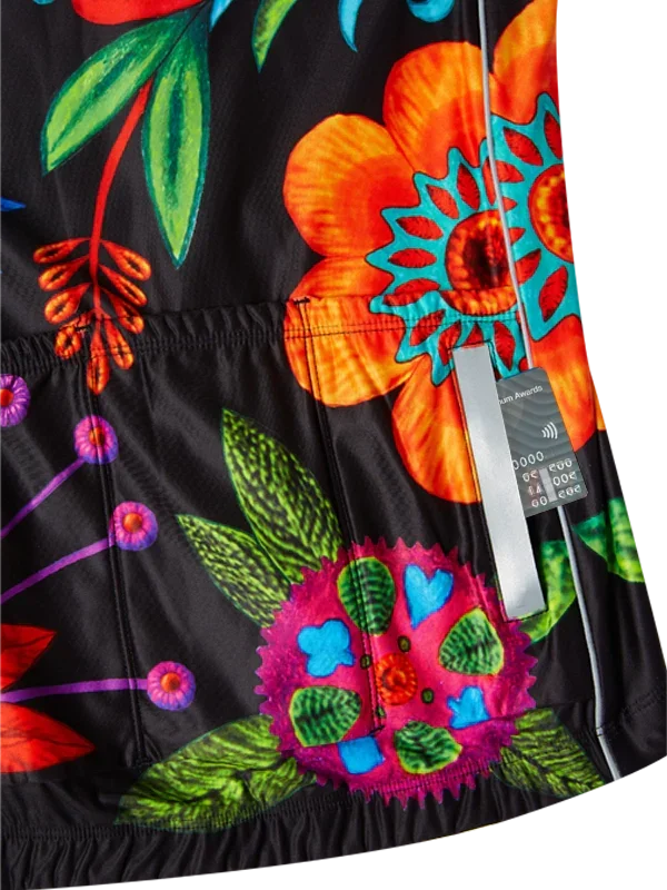 Vibrant floral cycling jersey with bold orange, pink, and green print on black fabric, featuring rear pockets and zipper.