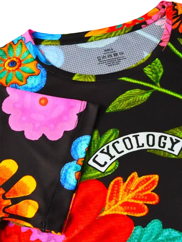 Vibrant floral cycling jersey with bold colors and 'CYCOLOGY' logo, perfect for women's bike wear.