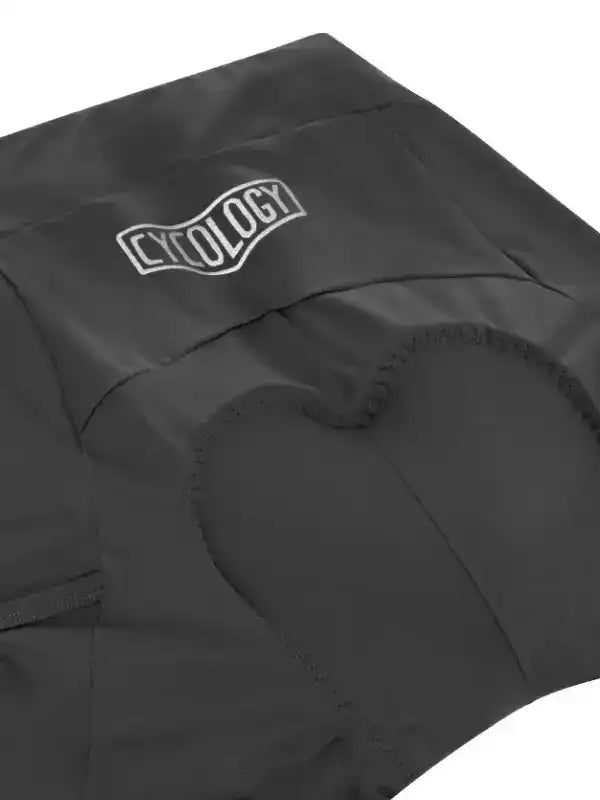 Black cycling shorts with padded seat and white Cycology logo, designed for comfort and performance.