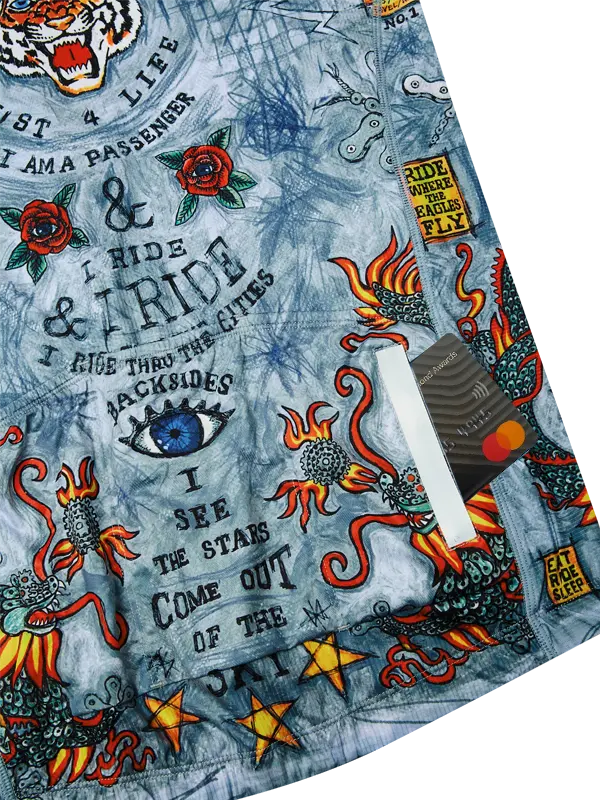 Close-up of fabric with tattoo-style designs, text, and symbols on a blue background.