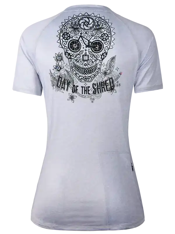 White cycling jersey with sugar skull design and 'Day of the Shred' text, featuring floral and gear details.