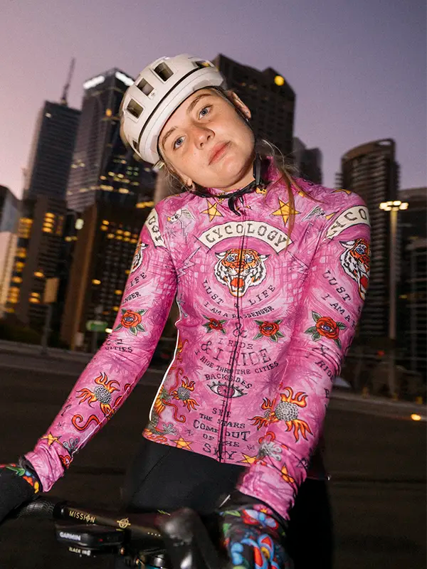 Person wearing a pink cycling jersey with a cityscape background