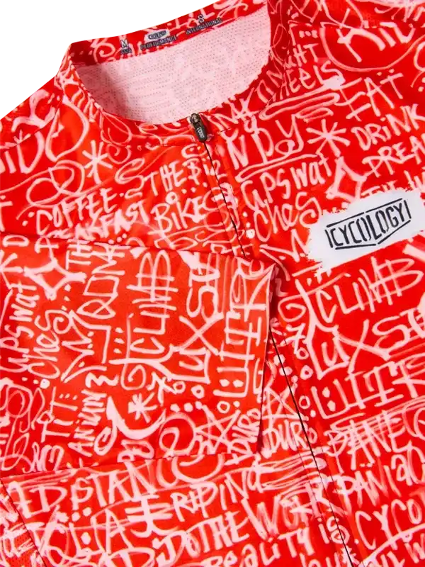 Red cycling jersey with white graffiti-style text and 'CYCOLOGY' logo, featuring bold design for men and women.