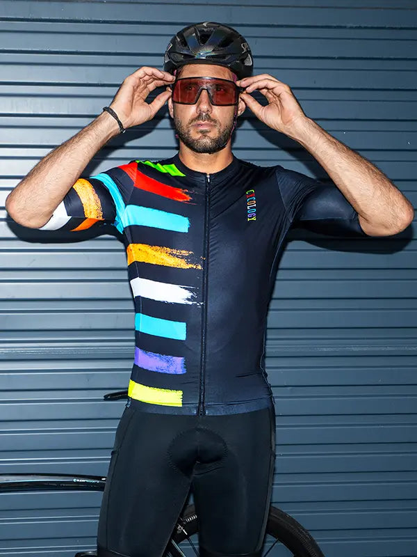 Person wearing a colorful Far Horizon Short Sleeve Men's Reborn  Cycling Jersey

outfit with a black helmet and sunglasses, standing against a blue background.