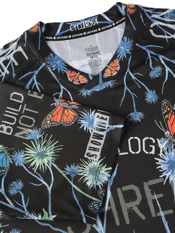 Black cycling jersey with butterfly and floral print, featuring bold text and breathable fabric design