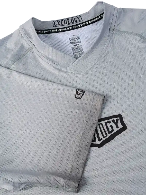 Grey men's cycling jersey with black logo, breathable mesh fabric, V-neck design for performance rides
