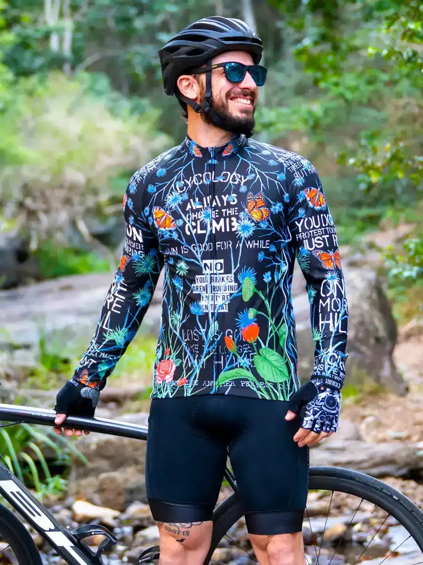 Men's long sleeve cycling jersey with floral and butterfly print, worn outdoors with helmet and sunglasses