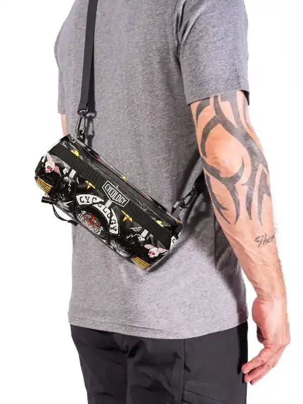 Men's tactical-style crossbody bag with bold graphic print, worn over shoulder for urban or cycling use.