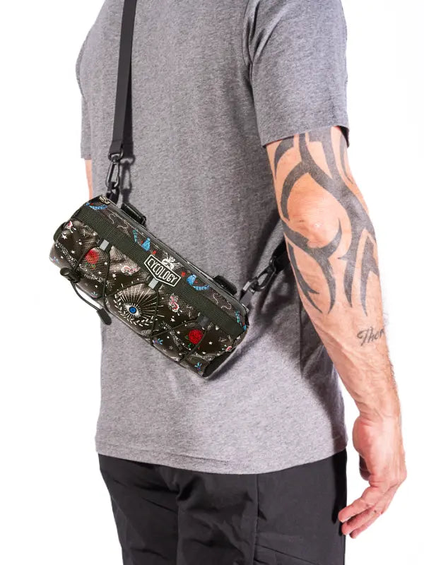 Person wearing a crossbody handlebar bag with colorful designs and 'Cycology' branding  