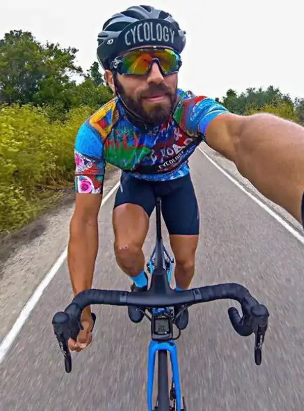 Man cycling in colorful jersey and helmet on road, wearing performance cycling gear