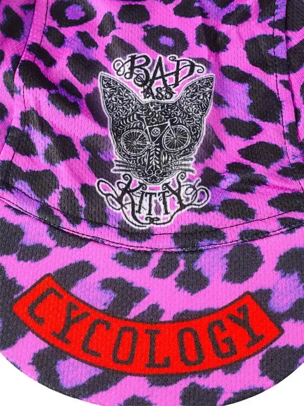 Purple leopard print cycling jersey with 'Bad Ass Kitty' cat graphic and red 'Cycology' patch