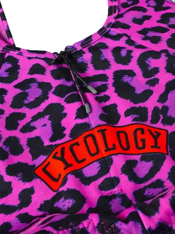 Vibrant pink leopard print cycling top with bold 'CYCOLOGY' logo, featuring drawstring neckline for adjustable fit.