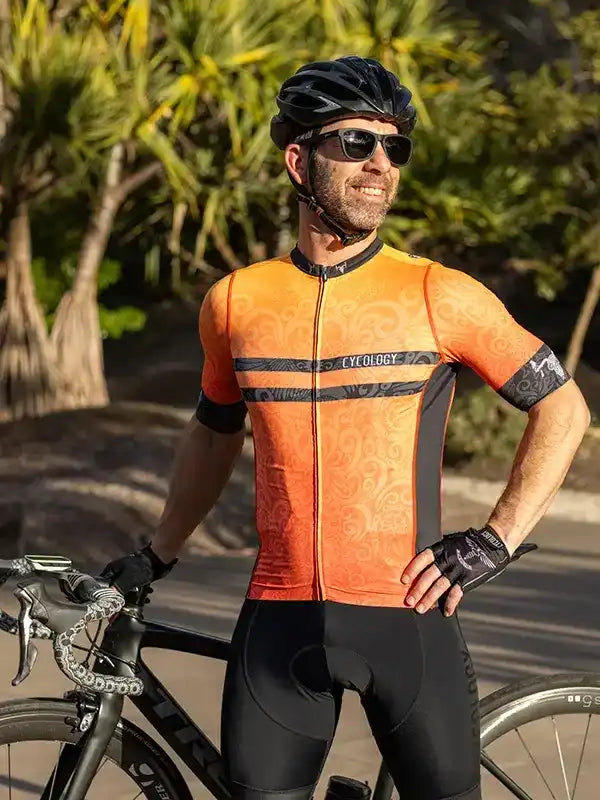 Man in orange cycling jersey and black bib shorts with bike, outdoor ride gear