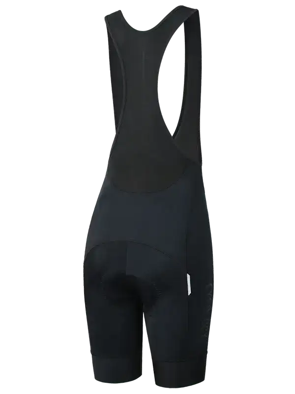 Women's black cycling bib shorts with a wide shoulder strap and a vertical 'CYCOLOGY' logo printed on the lower left leg shown from the back 