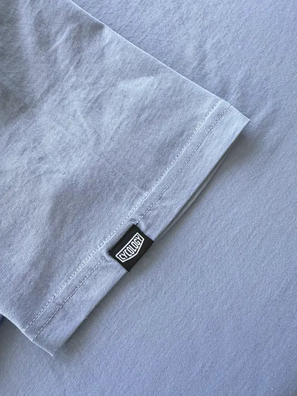 Close-up of a light blue  shirt with a brand label on sleeve