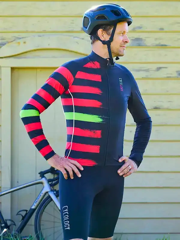 Man wearing red and black striped cycling jersey with green accents, paired with black shorts and helmet
