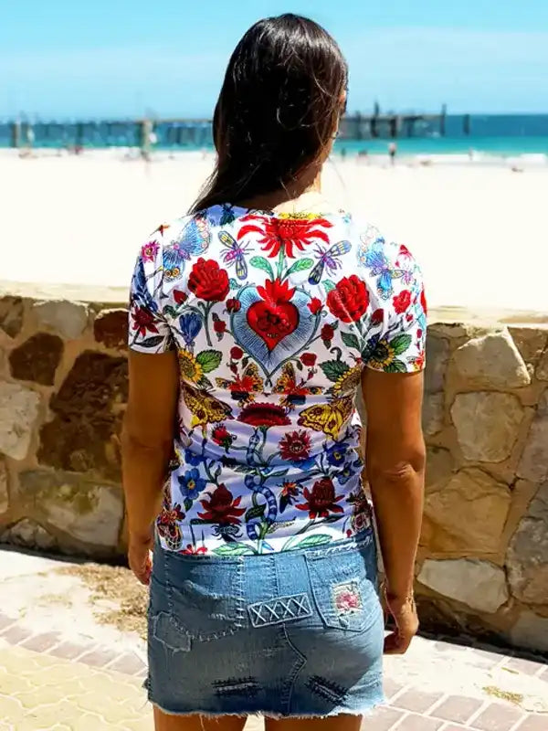 Woman wearing floral print cycling jersey with heart design, beach backdrop, stylish active wear